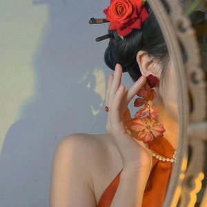 Detail of elegant red fabric rose earrings and matching hairpin on a model with classic style