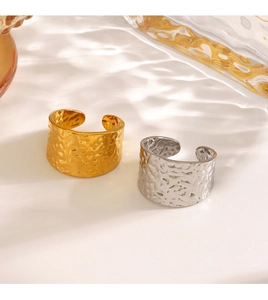 Macro detail of gold and silver hammered stainless steel wide open rings with wavy texture