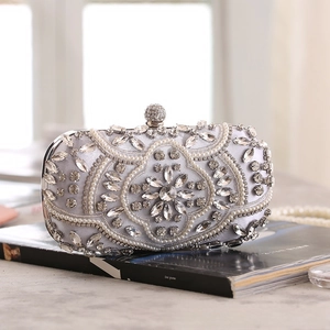 Macro detail of silver satin clutch with intricate pearl floral beadwork and crystal lock