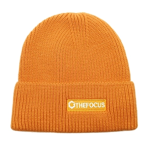 Close-up of bright orange ribbed knit beanie featuring the THE FOCUS patch logo