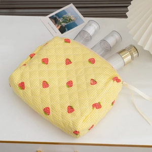 Detail of yellow checkered quilted cosmetic bag with strawberry print and bow detail