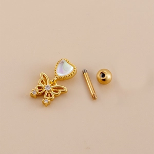 Detailed macro view of gold butterfly and heart cartilage stud with threaded screw ball