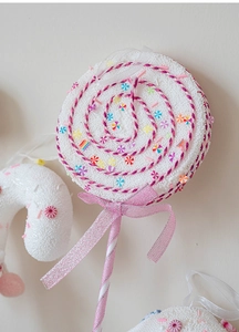 Detail of a white foam lollipop ornament with colorful candy dots and a pink glitter bow