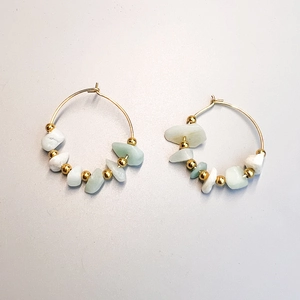 Detailed shot of golden hoop earrings featuring natural green and white stone chips