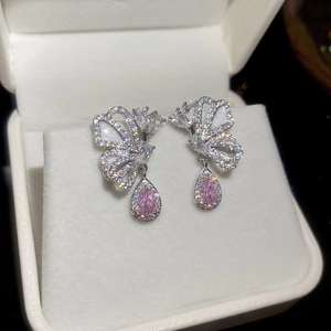 Detailed close-up of butterfly earrings with silver metal and pink teardrop stones