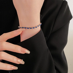 Detailed view of elegant blue gemstone bracelet worn on wrist over a black suit cuff