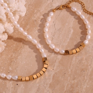 Detailed macro view of white irregular pearls and golden cube metal beads on a stone surface