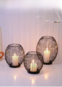 Close-up of black hollow metal candle holder set with glowing candles and wall shadows