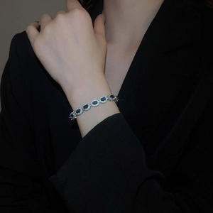 Détail d'un bracelet coulissant ovale en zircon avec pierre bleue sur une veste noire