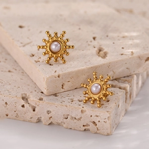 Macro view of gold sunburst stud earrings with white pearl center on stone