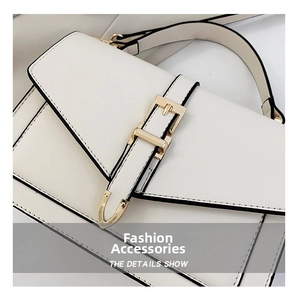 Detail showing white leather handbag with black contrast edges and gold metal buckle