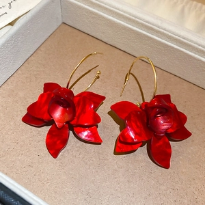 Macro shot of red resin flower earrings with marble texture on beige display tray