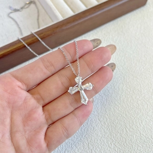 Detailed close-up of a silver cross pendant with five inlaid zircon stones held by hand