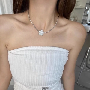 Detail of silver beaded chain necklace with white flower pendant on a model's neck