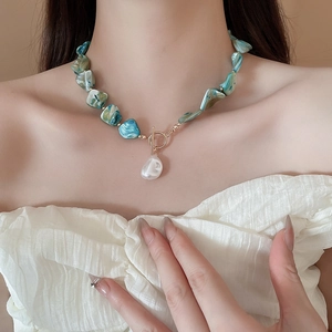 Detail of bohemian necklace with teal beads, gold T-bar clasp and baroque pearl pendant