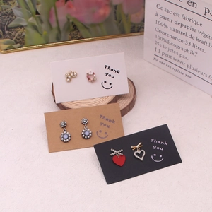 Detailed view of earring sets with pearls and rhinestones on card packaging with wooden decor