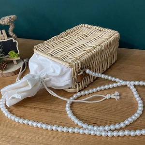 Handwoven rattan bag with white canvas drawstring pouch and large pearl chain strap