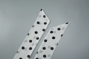 Close-up of white chiffon halter dress tie with black polka dot print and stitching