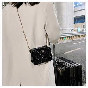 Girl's black PVC jelly bag with quilted pattern and gold chain strap in a travel setting