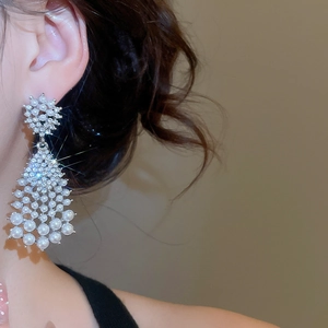Detailed view of elegant drop earrings featuring pearls and sparkling crystals on ear