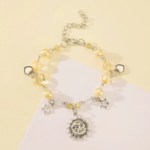 Detail of silver beaded bracelet featuring sun face charms and heart-shaped pendants