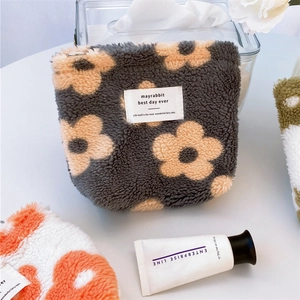 Macro shot of dark grey plush floral organizer pouch with embroidery and white woven label