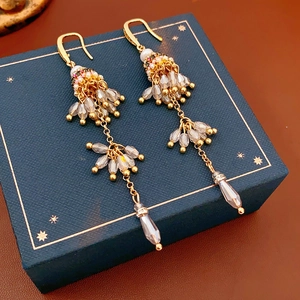 Détail de boucles d'oreilles bohèmes vintage à pompons et perles sur boîte cadeau bleue