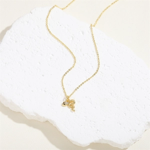 Detail of 14K gold snake pendant necklace with white zircons on a white gypsum stone