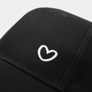 Black cotton baseball cap with white heart embroidery detail for a minimalist look