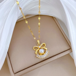 Detail of gold bow necklace with pearls and pavé zircons on beige jewelry box display