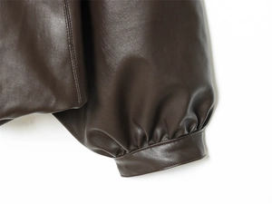 Detail of dark brown PU leather jacket showing sleeve cuffs and reinforced stitching texture