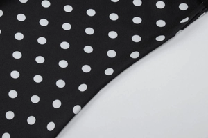 Détail d'un tissu vintage noir à pois blancs avec une texture textile de qualité