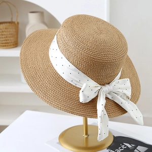 Détail du chapeau de paille français avec ruban à pois sur une texture tissée élégante