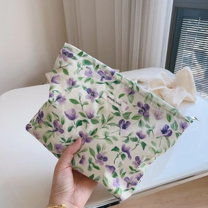 Detail of floral cotton makeup bag with zipper and simple wish label held in hand