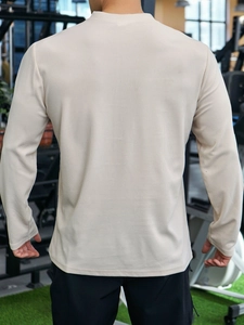 Rear view of men's beige waffle knit polo shirt showing textured fabric and fit in gym