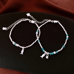 Dettaglio di bracciali in argento S925 con perline blu e ciondoli a pesce su velluto nero
