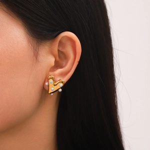 Vue macro de boucles d'oreilles cœur dorées avec perles blanches sur un mannequin