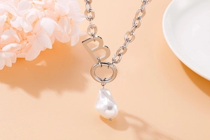 Close-up of silver chain necklace featuring a metal letter B and baroque pearl pendant
