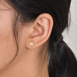 Elegant gold-plated stud earring with white round pearl shown on a female model's ear