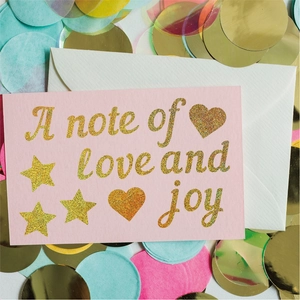 Detail view of 1-inch glitter alphabet stickers on pink greeting card with gold foil texture
