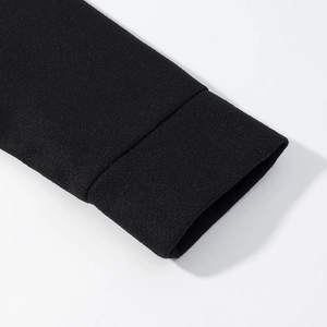 Gros plan des poignets en maille noire épaisse montrant la texture et densité de la veste