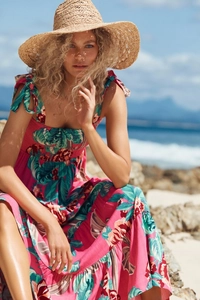 Close-up of tropical floral print on pink summer dress with bow straps and beach vibe