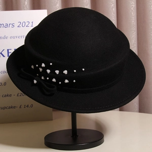 Detail of wool cloche hat showing decorative white flowers, pearls and ribbon bow