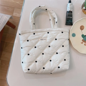 Flat lay of white quilted puffer tote bag with black polka dots and simple wish label