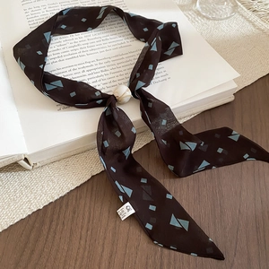 Close-up of brown chiffon scarf necklace with blue geometric patterns and resin buckle
