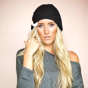 Detailed view of black knitted beanie featuring leaf pattern and lace button decoration