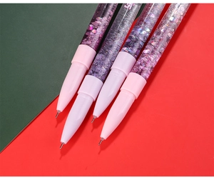 Dettaglio di penne viola con glitter liquidi e sabbie mobili su uno sfondo colorato