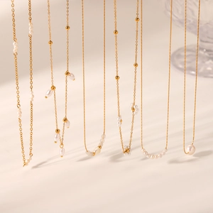 Detail showing multiple elegant gold chain necklaces with freshwater pearl accents