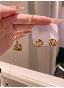 Detail of 18k gold plated necklace and square zircon earrings set held in hand