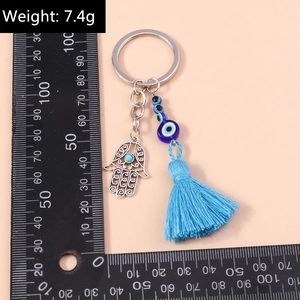 Macro detail of Hamsa Hand and Evil Eye keychain with blue tassel and turquoise beads